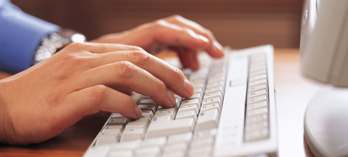 Hands typing on a computer keyboard